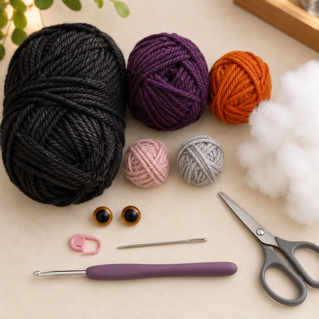 Charcoal, plum and orange yarn with crochet hook, safety eyes, stuffing and tools for the black cat pattern